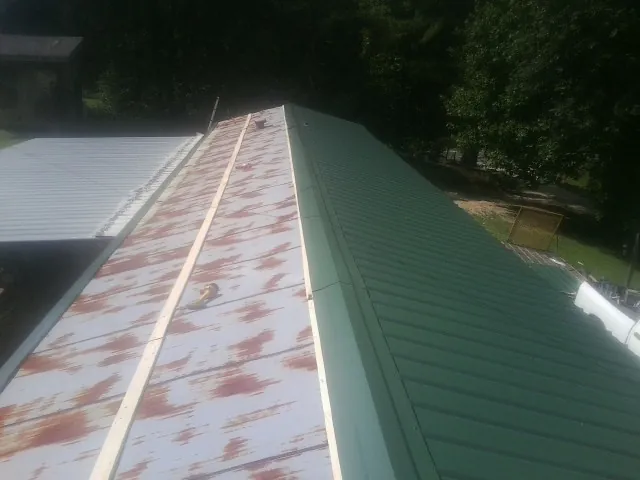 Old rusted panels beside newly installed green metal roofing — Wind Damage Roof Repair by Roofing Brothers in Punta Gorda