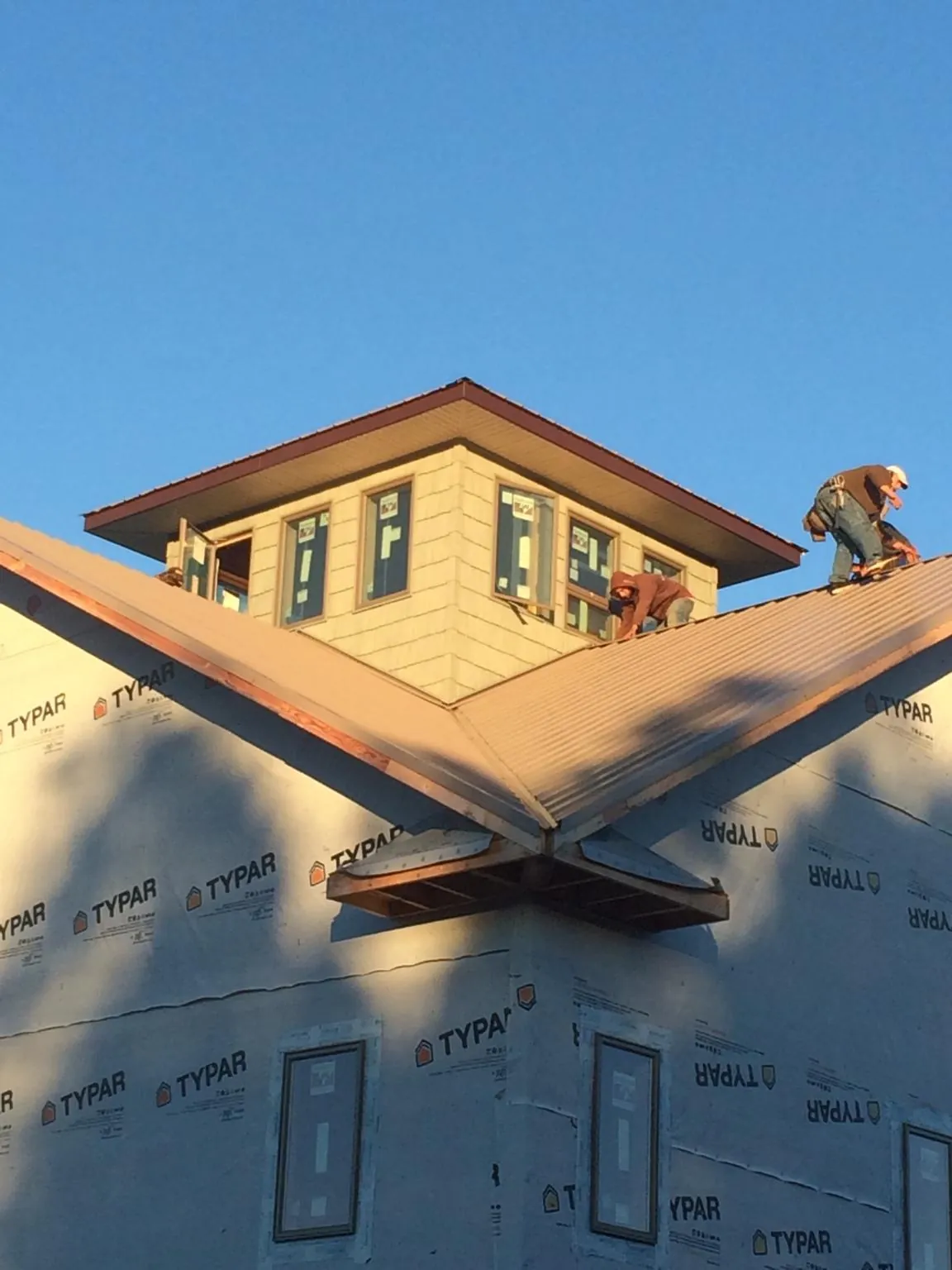 Roofers working around a rooftop cupola on a new metal roof at sunset — Roof Waterproofing in Punta Gorda by Roofing Brothers